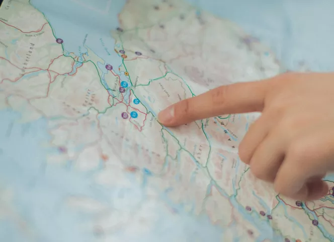 Carte d'une ville avec un doigt qui pointe un lieu précis
